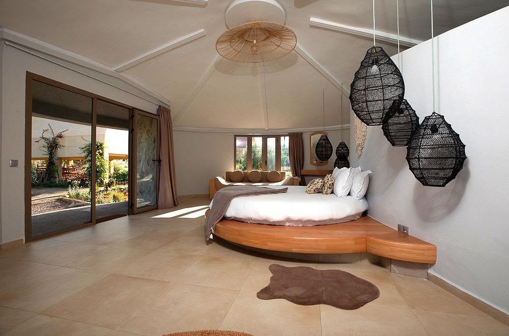 Chambre coupole avec lit rond sur estrade en bois et lanternes noires suspendues