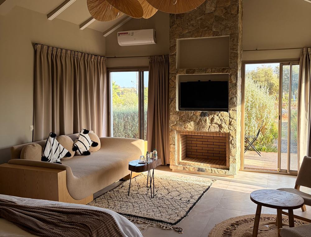 Chambre spacieuse avec cheminée en pierre, tapis berbère et grandes baies vitrées